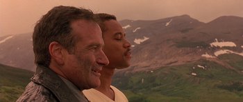 Movie still from “What Dreams May Come” (1998), directed by Vincent Ward – Two men standing next to each other in front of a mountain range; Close Up shot, Low angle
