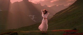 Movie still from “What Dreams May Come” (1998), directed by Vincent Ward – A woman in a white dress standing on top of a grass covered hill; Wide shot, Low angle