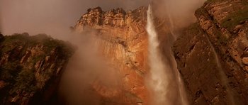 Movie still from “What Dreams May Come” (1998), directed by Vincent Ward – A large waterfall in the middle of a cliff; Extreme Wide shot, Low angle