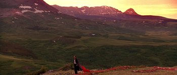 Movie still from “What Dreams May Come” (1998), directed by Vincent Ward – A woman standing on top of a grass covered hill; Extreme Wide shot, Low angle