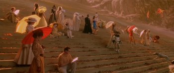 Movie still from “What Dreams May Come” (1998), directed by Vincent Ward – A group of people standing on some steps with an umbrella; Wide shot, High angle