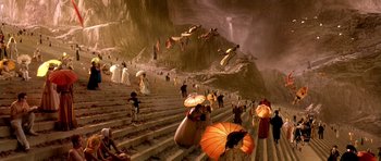Movie still from “What Dreams May Come” (1998), directed by Vincent Ward – A group of people standing on some steps holding umbrellas; Extreme Wide shot, High angle