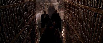 Movie still from “What Dreams May Come” (1998), directed by Vincent Ward – A group of people walking down a dark hallway; Wide shot, High angle