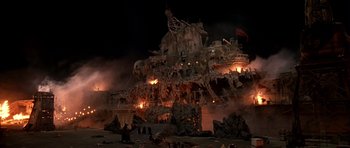 Movie still from “What Dreams May Come” (1998), directed by Vincent Ward – A large building that has been set on fire; Extreme Wide shot, High angle