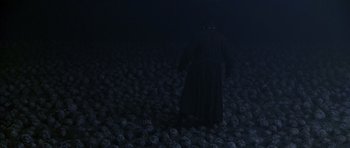 Movie still from “What Dreams May Come” (1998), directed by Vincent Ward – A man in a black robe standing in a pile of skulls; Extreme Wide shot, High angle