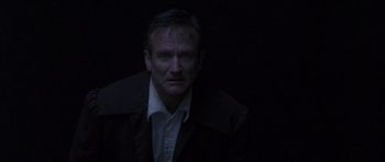 Movie still from “What Dreams May Come” (1998), directed by Vincent Ward – A man in a black jacket is looking at the camera; Close Up shot, Overhead angle