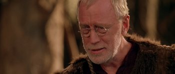 Movie still from “What Dreams May Come” (1998), directed by Vincent Ward – An older man wearing glasses and a fur coat; Close Up shot, Over the shoulder angle