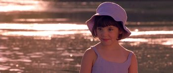 Movie still from “What Dreams May Come” (1998), directed by Vincent Ward – A young girl wearing a hat near a body of water; Close Up shot, Over the shoulder angle