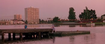 Movie still from “What Dreams May Come” (1998), directed by Vincent Ward – A man sitting on a dock in the middle of a lake; Extreme Wide shot, Low angle