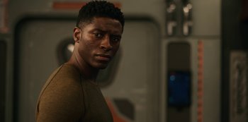 Movie still from “Another Life” (2019), created by Aaron Martin – A person wearing a brown shirt; Close Up shot, Over the shoulder angle