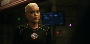 Movie still from “Another Life” (2019), created by Aaron Martin – A woman with blonde hair is standing in front of a television; Close Up shot, Over the shoulder angle