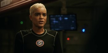 Movie still from “Another Life” (2019), created by Aaron Martin – A woman with blonde hair is standing in front of a television; Close Up shot, Over the shoulder angle