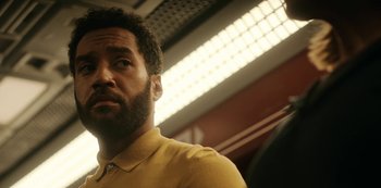 Movie still from “Another Life” (2019), created by Aaron Martin – A person wearing a yellow shirt; Close Up shot, Low angle