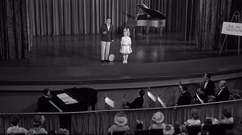Movie still from “What Ever Happened to Baby Jane?” (1962), directed by Robert Aldrich – Two people standing on a stage in front of a piano; Wide shot, High angle