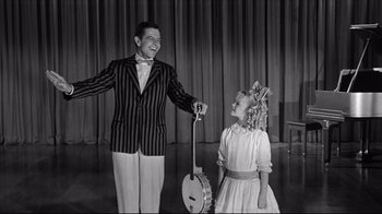 Movie still from “What Ever Happened to Baby Jane?” (1962), directed by Robert Aldrich – A man and a little girl standing next to each other on a stage; Medium shot, Over the shoulder angle