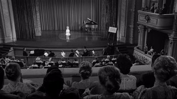 Movie still from “What Ever Happened to Baby Jane?” (1962), directed by Robert Aldrich – An audience watching a girl sing on a stage; Extreme Wide shot, High angle