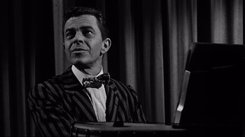 Movie still from “What Ever Happened to Baby Jane?” (1962), directed by Robert Aldrich – A black and white photo of a man sitting at a table; Medium shot, Low angle