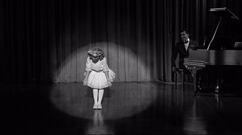 Movie still from “What Ever Happened to Baby Jane?” (1962), directed by Robert Aldrich – A little girl in a white dress and a man in a black suit; Wide shot, High angle