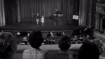 Movie still from “What Ever Happened to Baby Jane?” (1962), directed by Robert Aldrich – A couple of people are standing in front of an audience; Extreme Wide shot, High angle