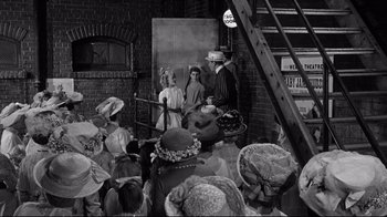 Movie still from “What Ever Happened to Baby Jane?” (1962), directed by Robert Aldrich – A group of people sitting in front of a brick wall; Wide shot, High angle