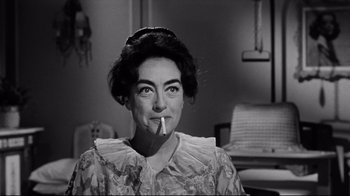 Movie still from “What Ever Happened to Baby Jane?” (1962), directed by Robert Aldrich – An older woman smoking a cigarette in a room; Close Up shot, Over the shoulder angle
