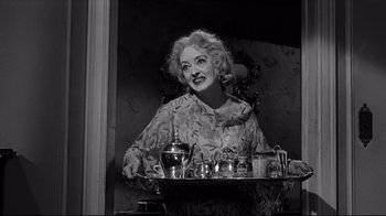 Movie still from “What Ever Happened to Baby Jane?” (1962), directed by Robert Aldrich – An older woman is holding a tray of tea; Medium shot, Low angle