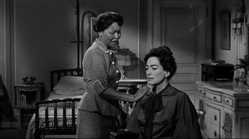 Movie still from “What Ever Happened to Baby Jane?” (1962), directed by Robert Aldrich – An old photo of a woman cutting another woman's hair; Medium shot, Over the shoulder angle