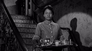 Movie still from “What Ever Happened to Baby Jane?” (1962), directed by Robert Aldrich – A woman sitting at a table with a tray of drinks; Medium shot, Low angle