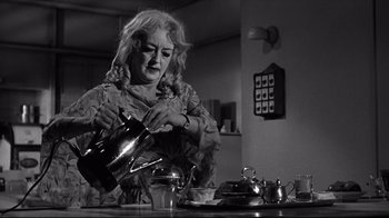 Movie still from “What Ever Happened to Baby Jane?” (1962), directed by Robert Aldrich – An older woman pouring tea into a tea pot; Medium shot, Low angle