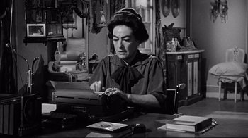 Movie still from “What Ever Happened to Baby Jane?” (1962), directed by Robert Aldrich – An older woman typing on an old fashioned typewriter; Close Up shot, Low angle