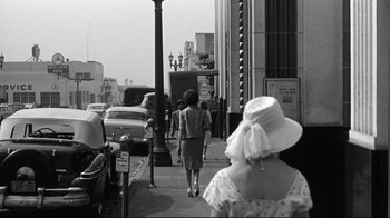 Movie still from “What Ever Happened to Baby Jane?” (1962), directed by Robert Aldrich – A black and white photo of people walking down the street; Wide shot, Low angle