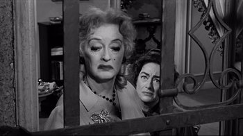 Movie still from “What Ever Happened to Baby Jane?” (1962), directed by Robert Aldrich – Two women are looking through a window at each other; Close Up shot, Low angle