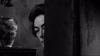 Movie still from “What Ever Happened to Baby Jane?” (1962), directed by Robert Aldrich – A woman with her eyes wide open looking at a wall; Close Up shot, Over the shoulder angle