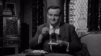 Movie still from “What Ever Happened to Baby Jane?” (1962), directed by Robert Aldrich – A black and white photo of a man drinking a cup of coffee; Medium shot, Low angle