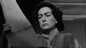 Movie still from “What Ever Happened to Baby Jane?” (1962), directed by Robert Aldrich – An older woman holding a piece of paper in front of her face; Close Up shot, Low angle