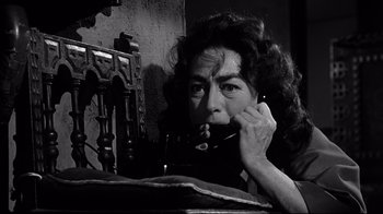 Movie still from “What Ever Happened to Baby Jane?” (1962), directed by Robert Aldrich – An older woman sitting in front of an old fashioned phone; Close Up shot, Low angle