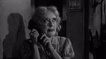 Movie still from “What Ever Happened to Baby Jane?” (1962), directed by Robert Aldrich – An older woman talking on a phone while holding a chain; Close Up shot, Low angle