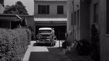 Movie still from “What Ever Happened to Baby Jane?” (1962), directed by Robert Aldrich – An old photo of a man and a woman standing in front of an old car; Extreme Wide shot, Low angle