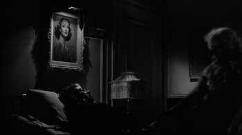 Movie still from “What Ever Happened to Baby Jane?” (1962), directed by Robert Aldrich – A woman laying on a bed next to a lamp; Medium shot, Over the shoulder angle