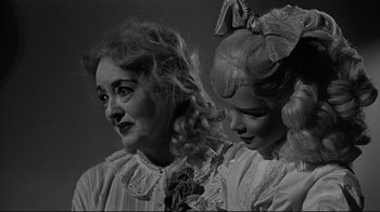 Movie still from “What Ever Happened to Baby Jane?” (1962), directed by Robert Aldrich – A woman and a girl are standing next to each other; Close Up shot, Over the shoulder angle