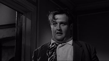 Movie still from “What Ever Happened to Baby Jane?” (1962), directed by Robert Aldrich – A black and white photo of a man in a suit and tie; Close Up shot, Low angle