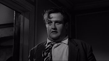 Movie still from “What Ever Happened to Baby Jane?” (1962), directed by Robert Aldrich – A black and white photo of a man in a suit and tie; Close Up shot, Low angle