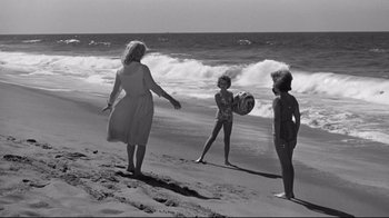 Movie still from “What Ever Happened to Baby Jane?” (1962), directed by Robert Aldrich – A woman and two young children on the beach; Wide shot, High angle