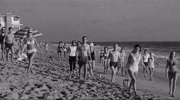 Movie still from “What Ever Happened to Baby Jane?” (1962), directed by Robert Aldrich – A group of people walking along the beach; Wide shot, High angle