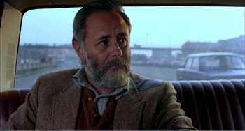 Movie still from “What Have I Done to Deserve This?” (1984), directed by Pedro Almodóvar – An older man sitting in the back seat of a car; Close Up shot, Over the shoulder angle