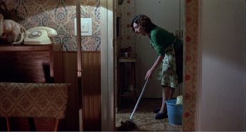 Movie still from “What Have I Done to Deserve This?” (1984), directed by Pedro Almodóvar – A woman is sweeping the floor with a mop; Wide shot, High angle