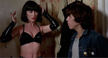 Movie still from “What Have I Done to Deserve This?” (1984), directed by Pedro Almodóvar – A woman in a black bra and a man in a leather jacket; Medium shot, Over the shoulder angle