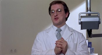 Movie still from “What Have I Done to Deserve This?” (1984), directed by Pedro Almodóvar – A man in a white lab coat clapping his hands; Medium shot, Low angle