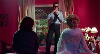 Movie still from “What Have I Done to Deserve This?” (1984), directed by Pedro Almodóvar – A man standing in front of two other people; Wide shot, Low angle