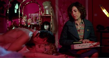 Movie still from “What Have I Done to Deserve This?” (1984), directed by Pedro Almodóvar – A woman sitting on a bed next to a man and a woman; Medium shot, Over the shoulder angle